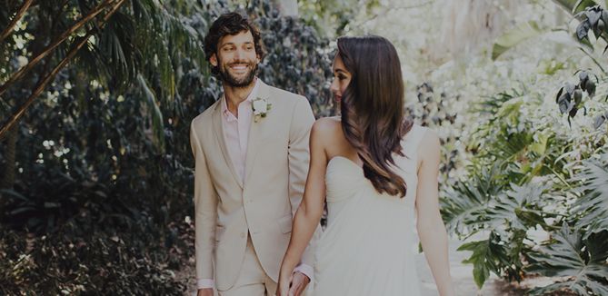 attractive couple in a jungle wearing light outfits and eyeing each other on their wedding day